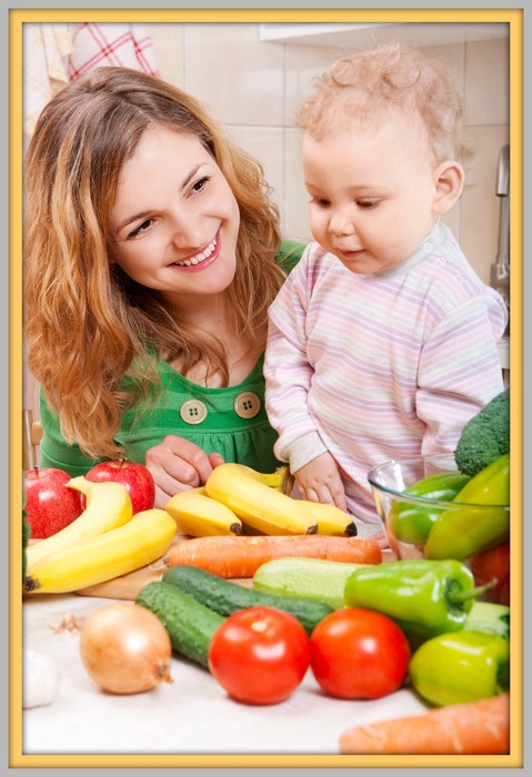 Happy mother with baby daughter preparing vegetable salad