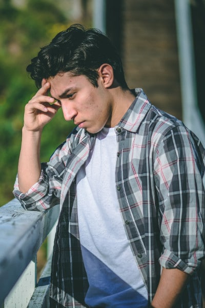 serious young man leans on railing in thought