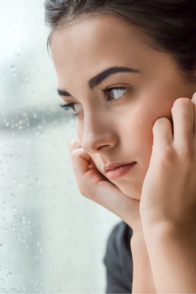 brunette contemplates near rainy window