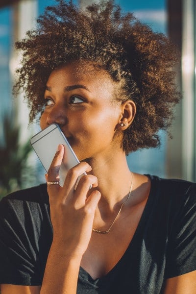 smiling young black woman holds cell phone