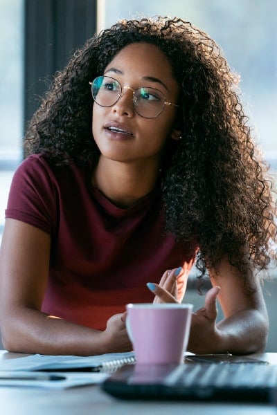young black woman with questions near laptop and coffee mug
