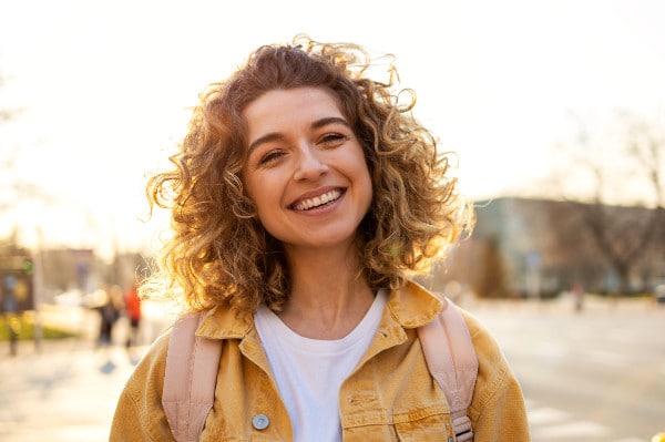 blonde college student with backpack smiles on campus