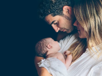 adoptive parents hold newborn baby in their arms