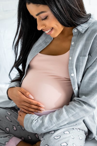pregnant woman cradles her belly and smiles