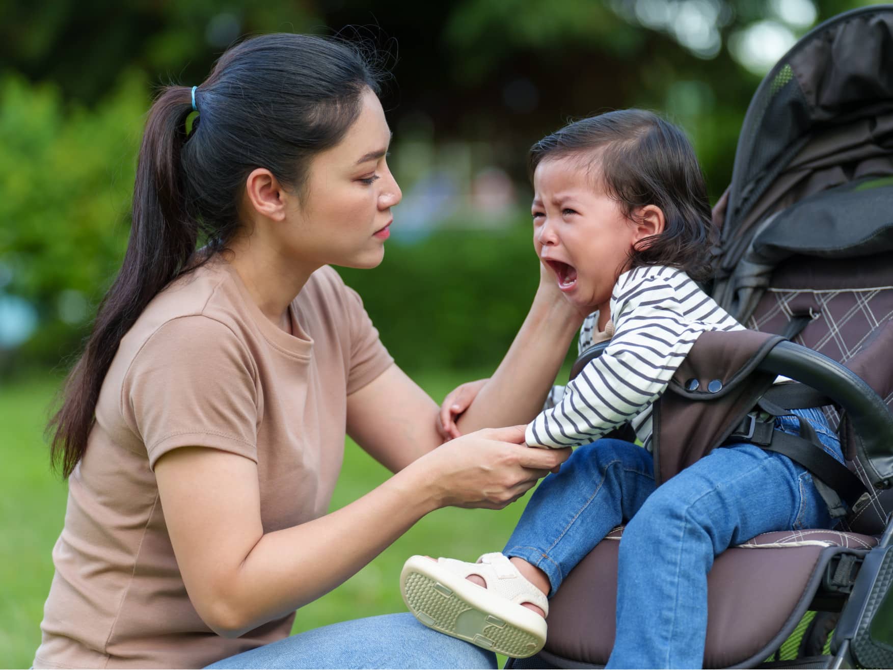 Toddler throwing tantrum in stroller is comforted by Mom
