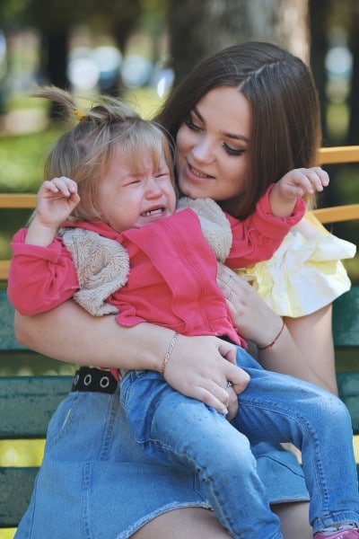 Toddler throws tantrum at park while mom holds her