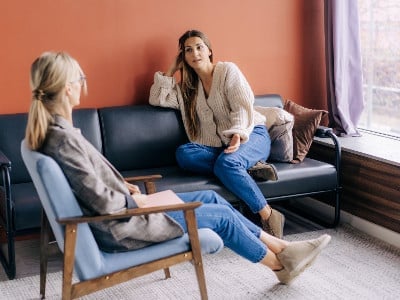 woman on sofa shares her story with female counselor
