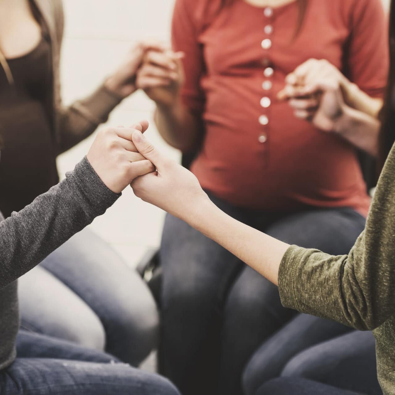 Four women sitting in a circle holding hands