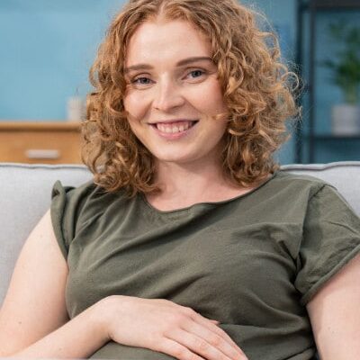 Happy young pregnant woman learning on laptop