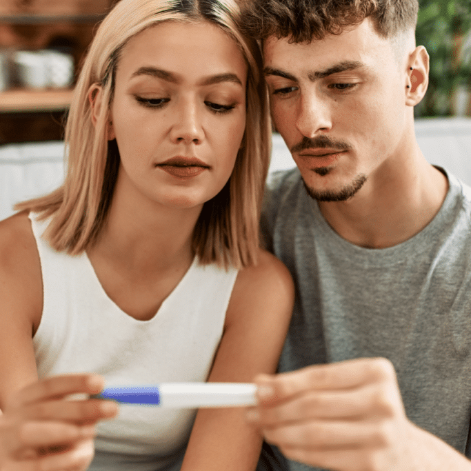 serious young couple looks at their pregnancy test