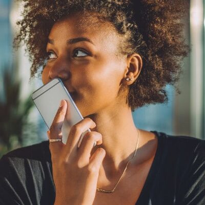 smiling young black woman holds cell phone