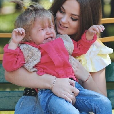 Toddler throws tantrum at park while mom holds her