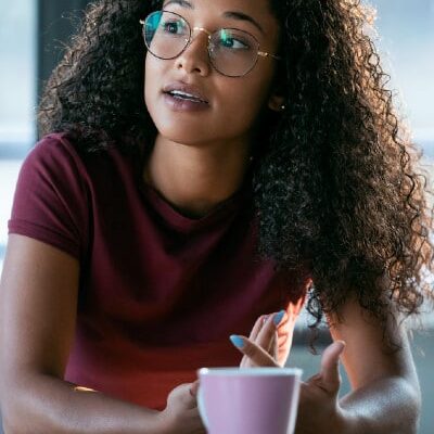 young black woman with questions near laptop and coffee mug